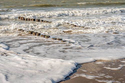 Schuimende golven in de branding aan zee