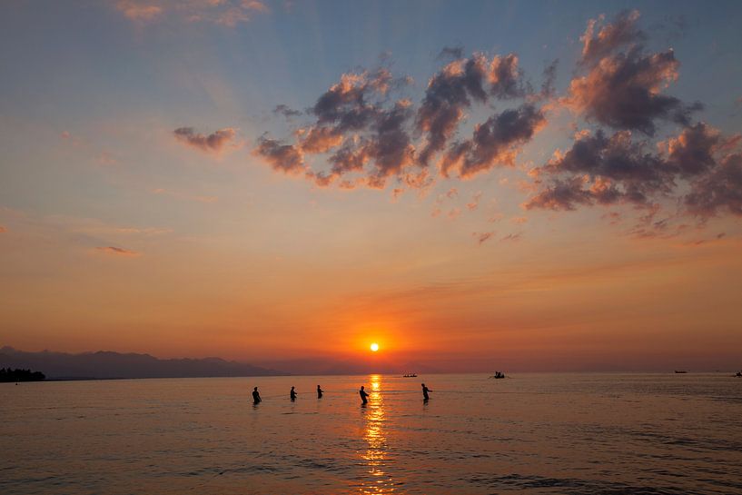 Fishermen pull up a net on the beach, to catch fish on the beach at sunset, Kuta, Bali. by Tjeerd Kruse