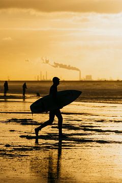 Silhouette van surfer die naar het water loopt in Scheveningen van Sander de Vries