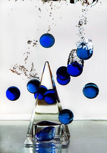 Glass pyramid with blue marbles in water.