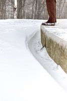 Een man staand op een cementenbalk met sneeuw