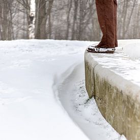 Een man staand op een cementenbalk met sneeuw van Thomas Winters