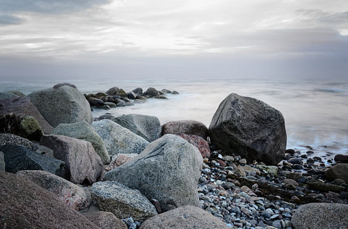 Steine an der Küste im Meer, weiche Wellen durch Langzeitbelichtung, Kopierraum