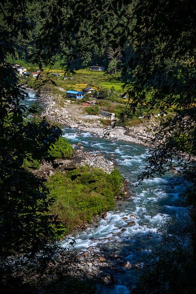 Woeste rivier raast langs dorpje. van Floyd Angenent