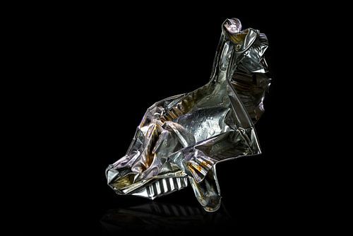 Aluminum foil tray of convenience food shown like an art sculpture against a black background, avoid