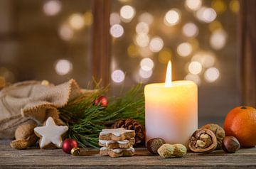 Christmas holiday background with candle and natural ornaments on wood with blurred light background by Alex Winter