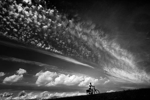 Radfahrender Mann vor einem Hintergrund aus Wolken