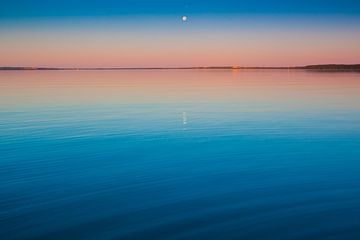 Het turquoise meer bij zonsopgang. glad blauw en turquoise meeroppervlak bij zonsopgang, rood en ora