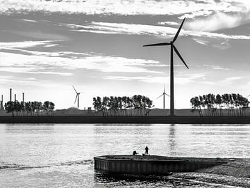 Silhouetten van een eenzame visser en windturbines in tegenlicht. (liggende opname) van John Duurkoop