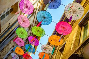 Bunte Regenschirme hängen als bunte Dekoration über der Straße