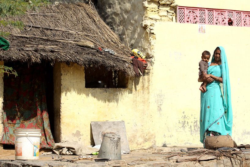 Woman with baby in front of their home by Cora Unk