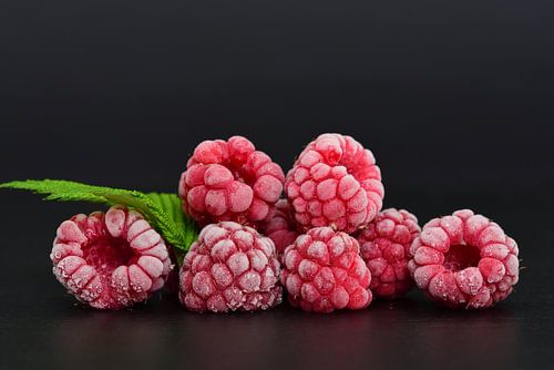 Frozen raspberries against a dark background