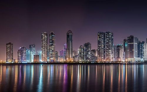 Skyline aan het water bij nacht, Sharjah, Verenigde Arabische Emiraten van Aloke Design