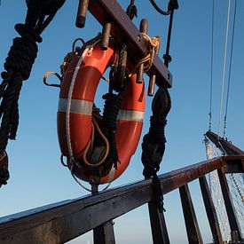 een oud houten schip met een rode reddingsboei van ChrisWillemsen