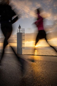 Hardlopers in het Gouden Avondlicht bij het IJsselmeer van Rik Brussel