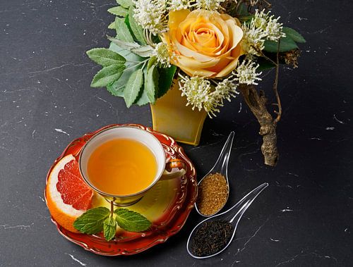 Zwarte thee met grapefruit in een kopje en lepeltje met rietsuiker