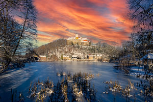 Burg Schönfels in Sachsen bei Sonnenuntergang im Winter mit Burgteich
