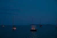 Zeilboten voor anker aan het strand bij maanlicht