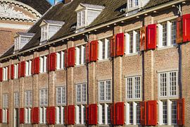 Ziegelfassade mit roten Fensterläden im goldenen Licht