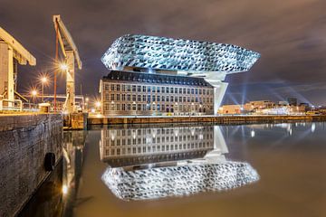 Verlichte Antwerpse Havenhuis 's nachts tot uiting in een kanaal van Tony Vingerhoets