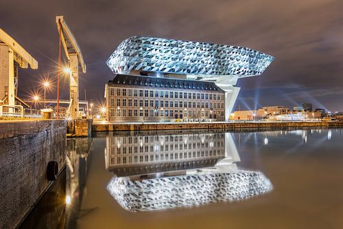 Illuminated Antwerp Port House at night reflected in a canal 