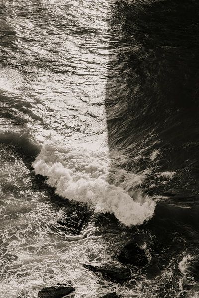 Zwart wit beeld van woeste golven in de namiddagzon van Moniek Kuipers