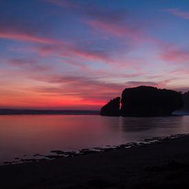 Silhouet reflecterende rots bij zonsondergang op een zandstrand van kall3bu