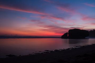 Silhouet reflecterende rots bij zonsondergang op een zandstrand van kall3bu