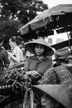 Vrouw verkoopt kruiden op de markt in Hanoi van Laurie Bosman