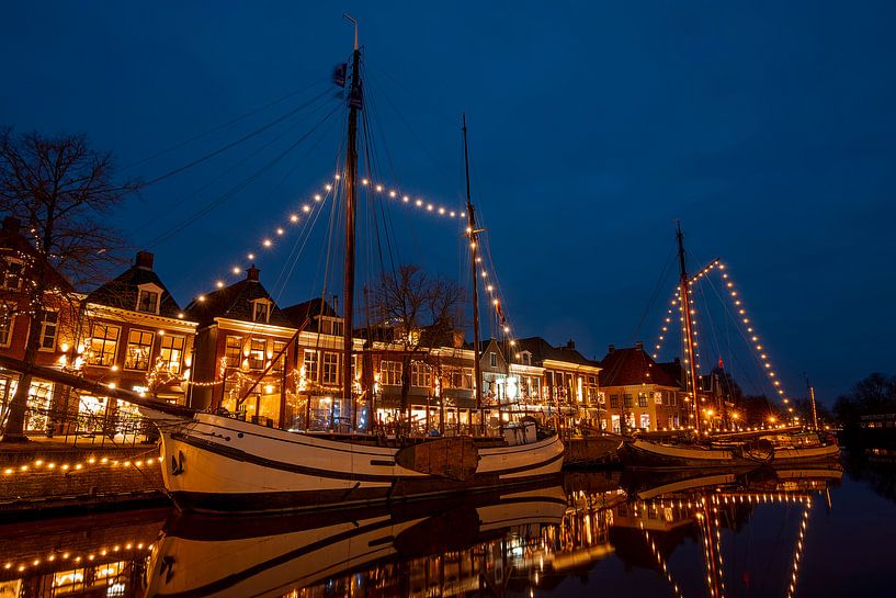 Decorated boats in the harbour of Dokkum in the Netherlands at night during Christmas time by Eye on You