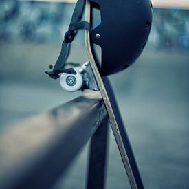 Skateboard with black helmet against a rail in skatepark by Mike Maes