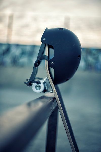 Skateboard met zwarte helm tegen een rail in skatepark van Mike Maes