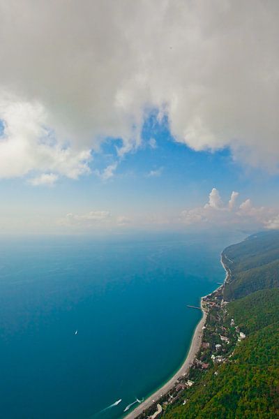 flying under the clouds along the turquoise sea and the green coast with many hotels. (aerial photo  by Michael Semenov