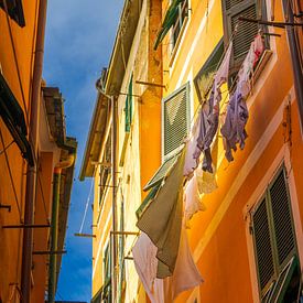 Zum Trocknen aus dem Fenster hängende Kleidung in einer sonnenbeschienenen Gasse in Vernazza von Robert Ruidl