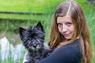 Meisje draagt zwarte hond op arm in park