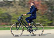 Een jonge vrouw fietst door het park in Amsterdam.  van Hamperium Photography thumbnail