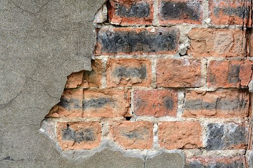 vervallen afbladderend pleisterwerk op het metselwerk van een huis