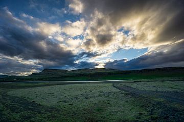 Iceland - Sun breaking through clouds over green volcanic landscape by adventure-photos