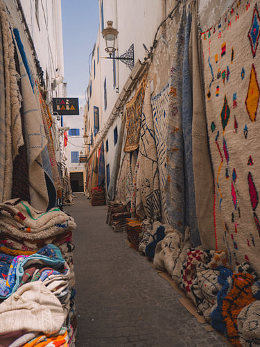 Enge Medina-Straße in Essaouira mit Berber-Teppichen – Marokko