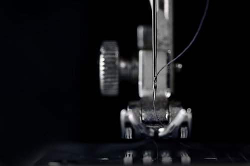 Nadel und Nähfuß einer Nähmaschine in der Vorderansicht als extreme Makroaufnahme, technische Erfind
