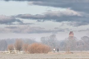 Wanderer genießen einen kalten Wintermorgen auf dem Landgoed Nienoord bei Leek mit dem Turm der Kirc