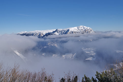 Sous un ciel d'un bleu éclatant, les montagnes enneigées émergent de la brume