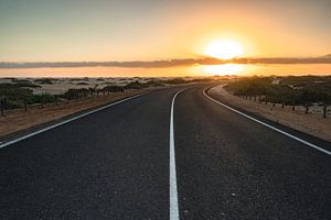 Schöner Morgen auf einer Straße durch die Dünen. Sonnenaufgang über einer Straße mit Wolken. Nationa