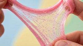 Hands stretching pink glitter slime with bubbles by Markus Gann