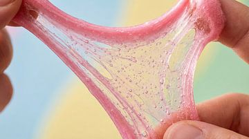 Hands stretching pink glitter slime with bubbles by Markus Gann