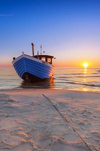 Blaues Fischerboot am Strand zum Sonnenaufgang