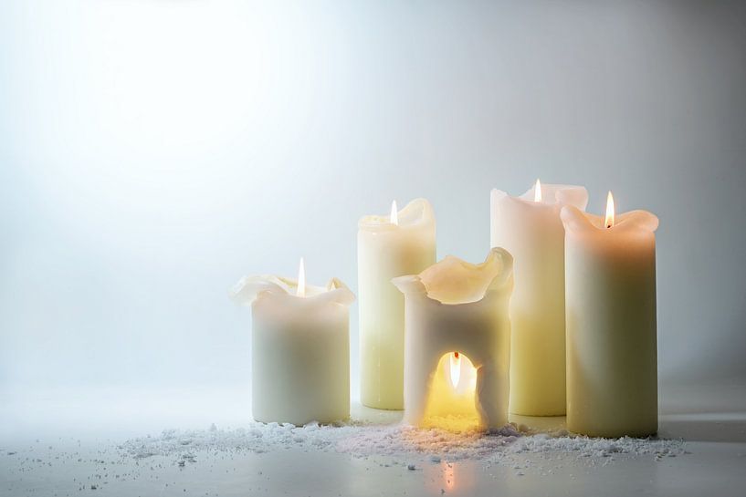 Groep witte kaarsen, één brandt er boven in een warme grot,  van Maren Winter