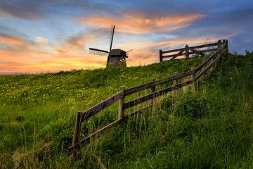 Holländische Mühle mit Zaun bei Sonnenuntergang