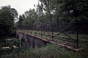 Eine alte Brücke mit einem entfernten Zug am Ende des Gleises