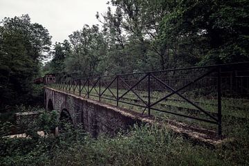 Een oude brug met een vergaande trein aan het eind van het spoor